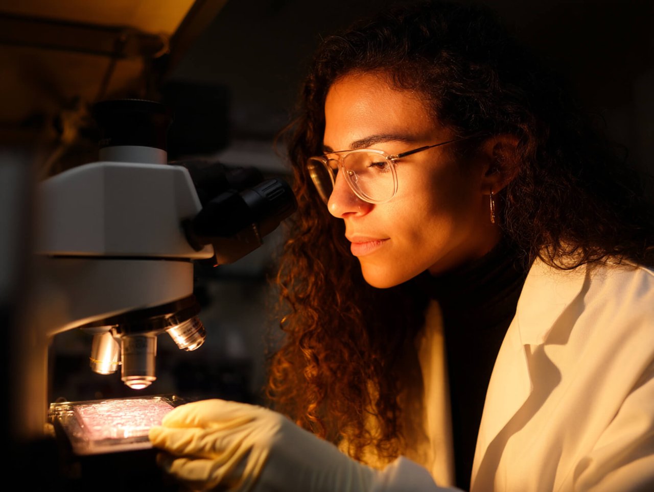 Eine Frau untersucht etwas unter dem Mikroskop.